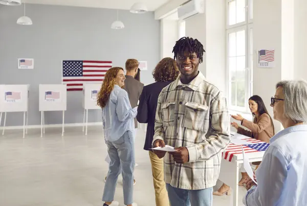 stock image Happy Americans at polling station. Young African American man standing in line with other people, looking at camera and smiling. USA, voting, United States of America, election concept