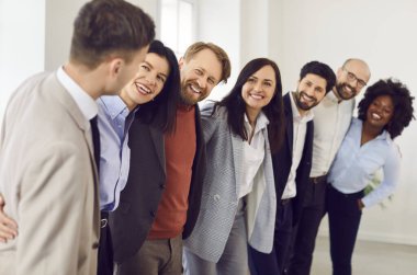 Neşeli işler, çok ırklı insanlar. Erkekler ve kadınlar ofiste sıraya girip gülümsüyor. Şirket çalışanları ya da bir grup personel toplantıda sarılıp sohbet ediyorlar. Takım çalışması konsepti.