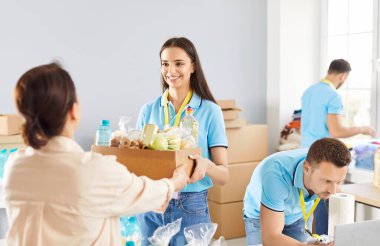 Hayır kurumunda çalışan ve yardıma ihtiyacı olan insanlara ücretsiz yiyecek bağış kutusu veren neşeli bir gönüllü. Kötü kavram için insani yardım, gönüllü yardım ve sosyal yardım.