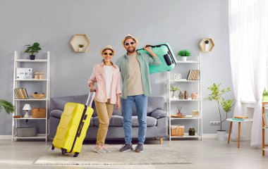 Mutlu, mutlu, güler yüzlü, evli ve bavullarını hazırlayıp yaz tatiline hazırlanan çift evdeki oturma odasında yan yana oturuyorlar. Seyahat, aile tatili konsepti