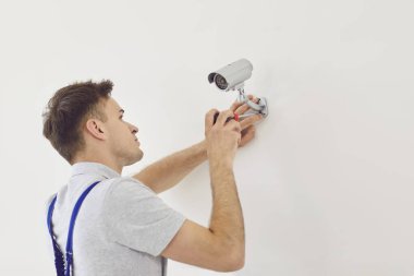Uzman, duvara güvenlik kamerası yerleştiriyor ve güvenlik sistemi kuruyor. Kapalı devre kamera, güvenlik ve izleme kapasitesinin arttırılması için ev veya ofis ortamında yerleştiriliyor..