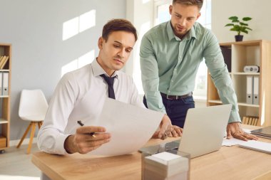 İş yerindeki işadamları. Masada dizüstü bilgisayarla çalışan iki genç çalışan yeni projeleri ya da girişimleri tartışan finansal belgeleri inceliyor, şirketi analiz ediyor..
