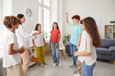 Gündelik giyinen bir grup öğrenci, bayan arkadaş canlısı bayan öğretmen veya psikologla aynı çemberde duruyorlar. Ergen çocuk sınıfta soru sormak ya da cevap vermek için elini kaldırıyor..
