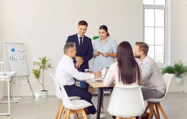 stock image Group of business people working with financial documents during a meeting. Company employees talking in office making great decisions with brainstorming. Coworkers listen to colleague at workplace.