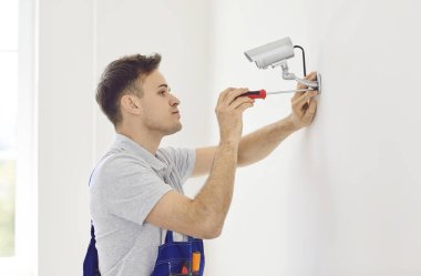 Duvarda tornavidayla duran profesyonel erkek teknisyen tarafından güvenlik kamerası kurulumu. Güvenlik kamerasının onarılması, modern ofis veya apartmandaki akıllı gözetleme sisteminin onarılması, montajı ve ayarlanması