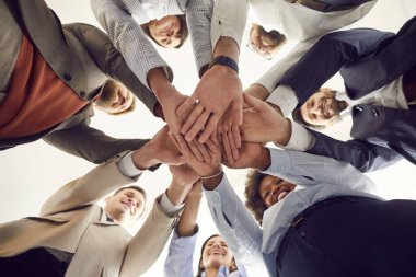Bir grup mutlu çok ırklı insan birlik ve takım çalışmasının göstergesi olarak daireler çizip el ele tutuşuyorlar. Takım oluşturma faaliyetlerindeki çeşitli şirket çalışanları başarılarını kutluyorlar. Düşük açı, aşağıdan.