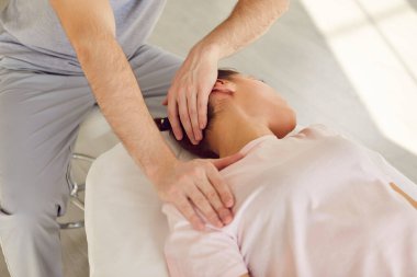 Nitelikli osteopat, kayropraktik uzmanı ya da manüel terapist genç bir kadının gergin kaslarını esnetmesine ve boyun ağrısını azaltmasına yardım ediyor. Terapi, kayropraktik, osteopati konsepti