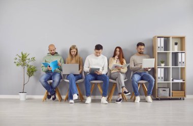 Bir grup zeki genç ofis sandalyesi oturuyor, laptoplarla birlikte çalışıyor, ekran ve kağıt izlemekle meşgul. Yeni işbirliği, gençlik takımı iş birliği, iletişimin paylaşılmasına katkı sağlayan danışmanlık