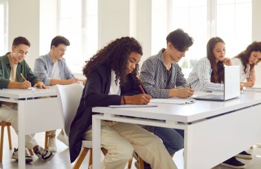 Bir grup çok ırklı öğrenci bir ders veya sınav sırasında bir okul sınıfında ders çalışmaya odaklandı. Öğrencilerin eğitime olan bağlılıklarını vurgulayan takım çalışması ve aktif öğrenme.