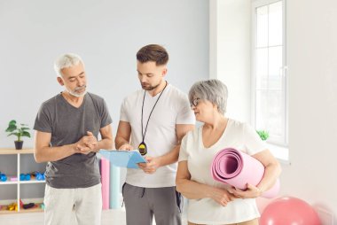 Erkek fizyoterapist, rehabilitasyon kliniğindeki sağlık çalışmaları için üst düzey erkek ve kadınlara danışıyor. Rehabilitasyondaki yaşlı insanlara yardım eden sağlık görevlisi..