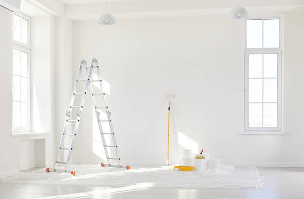 Empty room with painting equipment, brushes and colors for wall renovation during home or office construction project. Process of reconstruction and improvement in residential or commercial spaces.