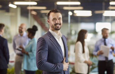 Kendine güvenen genç işadamı kalabalığın önünde kameraya bakıyor. Lobideki mutlu iş kadını. Kavramsal başarı, kendine güvenen adam, uzman insanlar.
