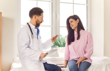 Bakıcı erkek doktor hastane ofisindeki kadın hastaya tıbbi bakım ve konsültasyon sağlar. Klinik ziyareti sırasında hastanın en iyi tıbbi tedaviyi almasını sağlayan hemşire.