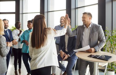 Mutlu profesyonel takım antrenörleri, başarılı bir sunumdan sonra kadın ve erkek birbirlerine beşlik çakıyor ya da konferans odasında çeşitli iş adamlarıyla birlikte iş eğitimi alıyorlar..