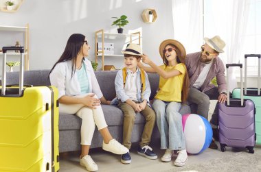 Mutlu aile, kahkahalar ve heyecanla oturma odasındaki kanepede bavullarıyla oturup gelecek yaz tatillerini bekliyor. Keyifli yolculuklar ve unutulmaz anlar bekliyor..