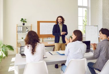 Genç üniversite öğrencileri ve sınıf arkadaşları masada oturup, ders sırasında erkek arkadaş canlısı okul öğretmenine cevap veren bir kızı alkışlıyorlar. Eğitim ve bilgi kavramı.