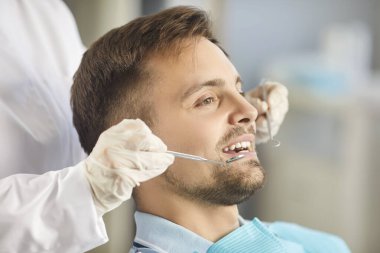 Dişçi doktor özel bir diş aleti kullanarak hastaların dişlerini ayrıntılı bir şekilde kontrol eder. Klinikte yapılan rutin muayeneler sırasında gerekli oral bakım ve dişçilik uygulamaları.