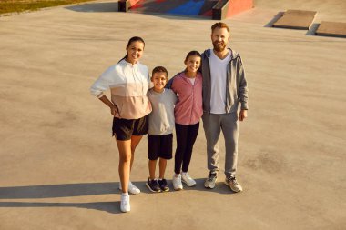 Spor kıyafetleri giyen mutlu ve sportif bir ailenin parktaki antrenmandan sonra neşeli bir şekilde kameraya bakışının en üst görüntüsü. Doğa konseptinde açık hava eğitimi ve uygunluğu.