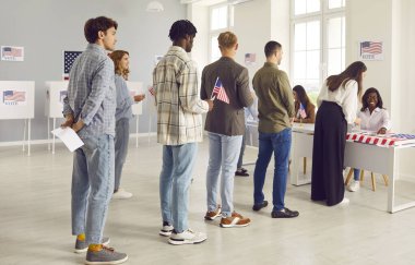 Seçim günü oy kullanma merkezinde Amerikan bayraklarını elinde tutan geniş bir grup gülümseyen insan. Amerikalı seçmenler ABD vatandaşları arasında oy merkezinde kuyrukta bekliyorlar.