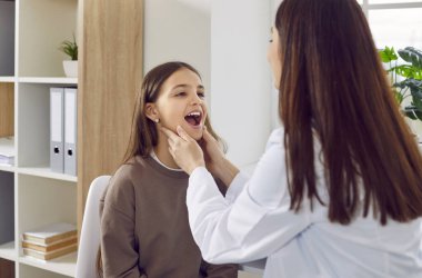 Doktor, çocuk hastayı KBB muayenesi yapıyor. Otolarolog kadın boğaz ağrısına bakabilmek için kızın ağzını açmasını istiyor. Pediatrik endokrinolog çocukların tiroid bezlerini inceliyor.