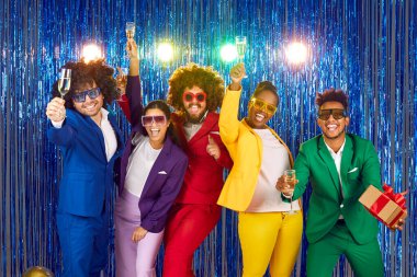 Portrait of multinational funny group of laughing happy cheerful people dressed in bright business suits, voluminous curly wigs and big disco glasses with rhinestones on shiny festive blue background. clipart