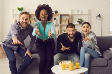 Çok ırklı insanlar evdeki kanepede oturup maç izliyorlar. Bir grup çok ırklı arkadaş TV 'de futbol maçı izleyip oyuncuları destekliyor ve favori takıma galibiyet getirecek golü bekliyorlar.
