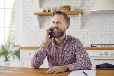 Mutlu Kafkasyalı adam evde oturup müşteri müşterisiyle cep telefonu hakkında konuşuyor. Gülümseyen orta yaşlıların akıllı telefonları vardır. Kaliteli mobil sağlayıcı bağlantıları vardır. İletişim.