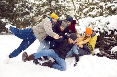 Dış giysili çok neşeli genç insanlar parkta aktif hafta sonlarında eğleniyorlar. Mutlu çeşitli arkadaşlar gülüyor kış tatilinin ya da karlı ormanda tatilin tadını çıkarın. Arkadaşlık, eğlence aktivitesi..