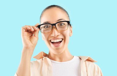 Gözlüklü, mutlu ve heyecanlı beyaz bir kadının portresi, mavi arka planda haykırıyor. Onun anlamlı göz giysisi ve neşeli davranışları bir anlık şaşkınlık ve haz yakalar..
