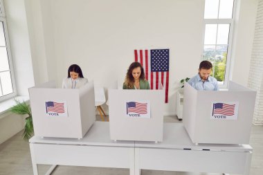 İnsanlar oy kabinlerinde durup Amerika seçimlerinde seçim yapmadan önce düşünüyorlar. Genç erkekler ve kadınlar seçimlerini federal seçimlerde sandık merkezinde yaparlar. Oylama ve demokrasi kavramı.