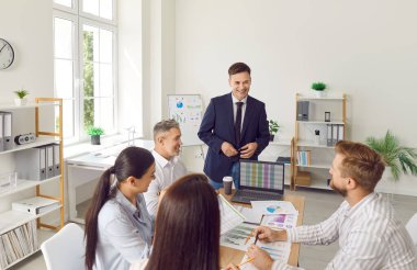 İş adamlarından oluşan bir ekip ofiste iş toplantısı yapıyor. Bir grup mutlu genç, pazarlama verilerini analiz ediyor ve yeni stratejiler geliştiriyor. İş, finans, pazarlama kavramı