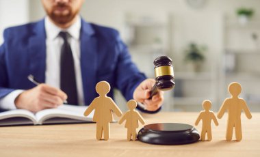 Aile mahkemesinde, bir avukat aile figürlerinin yanında elinde tokmak olan boşanma davaları hakkında bir karar verir, velayet, çocuklar ve adalete ilişkin hukuki hükmü sembolize eder..