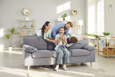 Neşeli, neşeli, mutlu aile, modern oturma odasında kanepede oynayan insanlar, eğlenen küçük kız, evlat gıdıklayan anne ve anne hafta sonları eğlenmek için aileleriyle birlikte gülen çocuklar.