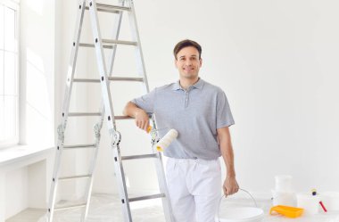 Ev tadilatı sırasında profesyonel ressam ya da tamirci olarak çalışan mutlu bir adamın portresi. İnşaat ve ev geliştirme projelerinde çalışan bir işçinin memnuniyeti ve becerisi.