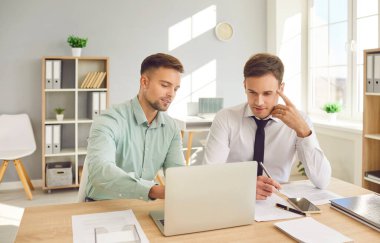 İş rehberliğinde çalışan mutlu erkek ofis ortakları, dizüstü bilgisayarla çalışan iş adamı. Yeni veya deneyimli girişimciler, serbest çalışanlar, öğrenciler ve yaratıcılar birlikte sunum yapmakla meşguller 
