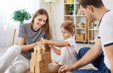 Pozitif aile evde vakit geçirip çocuklarıyla tahta oyuncaklarla oynuyor. Mutlu aile, eğlenceli ve etkileşimli oyun zamanıyla bağ kurmayı ve anılar yaratmayı sever..