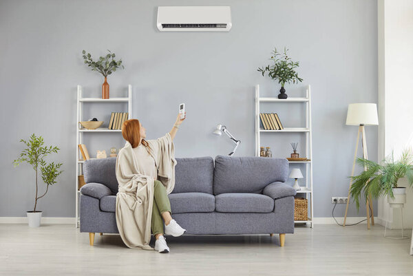 Девушка завернутая в одеяло включения, выключения кондиционера, дуть теплый воздух комнатный контроль температуры, регулировать оптимальную производительность, домашняя обстановка, обеспечивая идеальную систему климатического отопления в холодной плоской