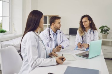 Masanın etrafında bir grup doktor ve hemşire hastane ofisinde konferans veriyor. Profesyonel klinik ekibi, sağlık ekibinin tıbbi uzmanlığını paylaştığı bir toplantı düzenliyor..