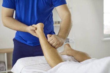 Masör hastaların bacağına masaj yapıyor. Profesyonel fizyoterapist, osteopat, masajcı, ya da ayak bileği masajı yapan masör, bacak ve baldır kasları. Kesilmiş atış. Fizyoterapi konsepti