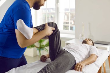 Modern masaj odasında kayropraktik uzmanı, osteopat ya da fizyoterapist ya da rehabilitasyon merkezinde hastayı muayene ediyor, ağrıyı tedavi ediyor ve diz esnekliğini kontrol ediyor. Fizyoterapi konsepti