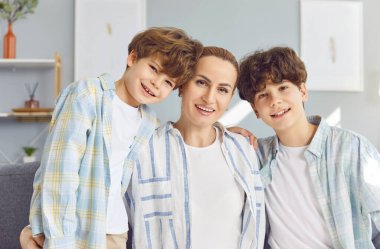 Mutlu anne, kadın ve genç, küçük çocuk aile fotoğrafı evde, stüdyo salonunda gülümsüyor. Kardeş çocuklar hafta sonları birlikte vakit geçiriyorlar, iyi aile ilişkileri var. 