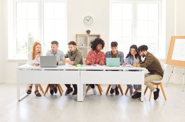 İş dünyasından profesyoneller ya da öğrenciler öğrenme ve işbirliği için dizüstü bilgisayarları kullanarak bir ofiste birlikte çalışırlar. Halkın çabaları, takım çalışmasının ve topluluğun başarıya ulaşmadaki önemi.