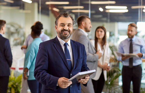 Уверенный бородатый зрелый серьезный бизнесмен, успешный руководитель компании, основатель, профессиональный докладчик, позирующий с документами, счастливый взгляд в камеру, корпоративный портрет бизнесмена на встрече