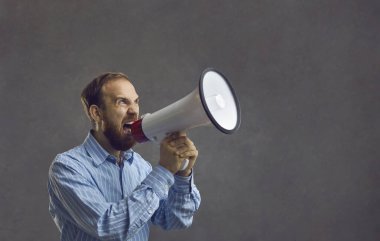 Bearded man in a blue shirt shouted loudly into a megaphone. An agitated salesperson, office worker, or corporate manager yells into a loudspeaker like crazy announcing a sale. On a black background. clipart