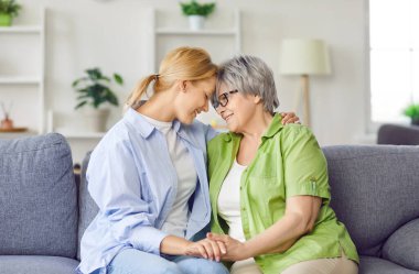 Yetişkin mutlu kız, evde yaşlı anneyi kucaklıyor, güçlü bir aile bağı var. Olumlu ilişkiler ve ebeveynler ve çocuklar arasındaki derin sevgi, aile sevgisinin sıcaklığını gösteriyor..