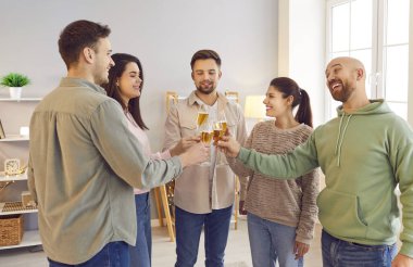 Bir grup genç arkadaş şarap kadehleri kaldırıyor ve evde bir çemberin içinde birlikte konuşuyorlar. Ev partisinde insanlar bir bardak şampanyayla kutlama yapıyorlar. Kutlama konsepti.