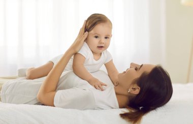 Sevgi dolu beyaz bir anne, küçük bir çocukla oynuyor. Evde yatakta birlikte rahatlıyorlar. Şefkatli anne, iyi istirahatler, yeni doğmuş bebeğe sarıl. Annelik, annelik izni kavramı.