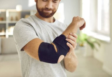 Kol askısı kırık, sağlıksız genç bir adamın evinde rehabilitasyonu var. Hasta adamın uzuvlarında yara ya da kemik kırığı olan bir bandaj var. Sağlık ve Tıp Konsepti.