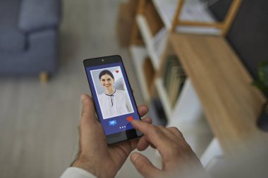 Çevrimiçi aşk. Kapanış adamı kırmızı kalp tuşuna basıyor ve sosyal medya sitesinde veya mobil flört uygulamasında gülümseyen genç kadınların fotoğrafını veriyor. Eller cep telefonunu yakın çekimde tutsun.