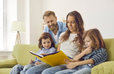 Birlikte mutlu aile kitapları okuyoruz. Anne, baba ve iki küçük çocuk evlerinde rahat yeşil koltukta oturup fotoğraf albümüne, ansiklopediye ya da ilginç hikayelerin ve eğlenceli gerçeklerin kitabına bakıyorlar.